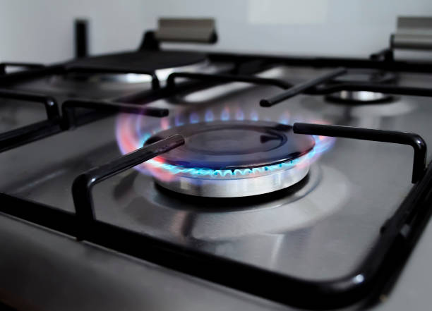 Gas stove burner with blue and red flame. Modern kitchen black and silver stove with gas on. Gas range burning flame. Close look on gas burner. gas stove burner stock pictures, royalty-free photos & images