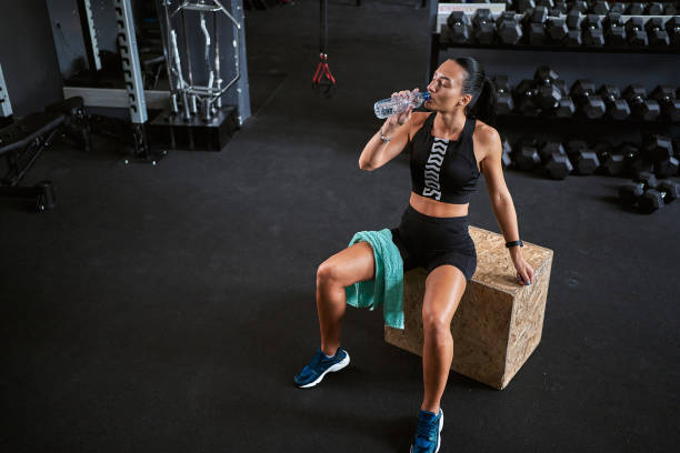 istock Young female athlete drinking water while taking a break from exercising at the gym 1278404197