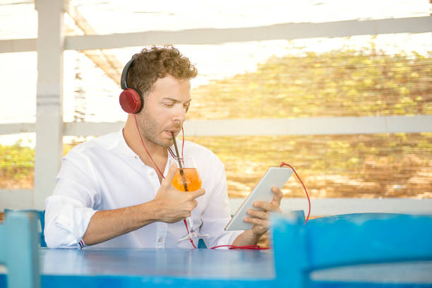istock Young caucasian european guy dinking cocktail working with tablet in a beach bar 1278406351