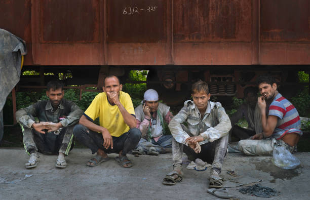 Mathura, India - October 13, 2019:  Manual workers employed to move heavy bags of cement enjoy a break alongside railroad on October 13, 2019 in Mathura, Uttar Pradesh, India.