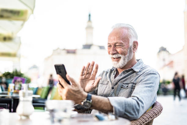 istock Happy senior man using phone for a video call at cafe. 1278412742