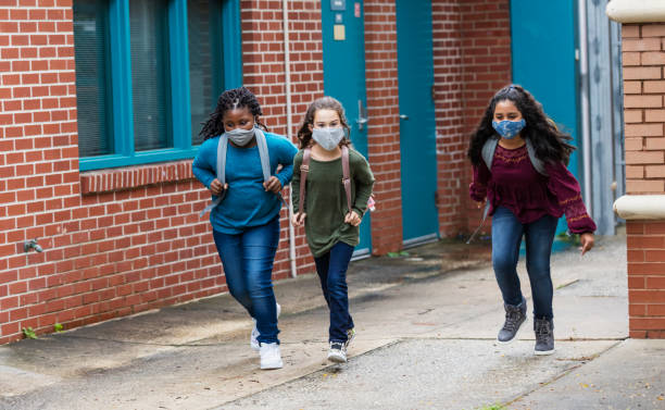istock Girls running outside elementary school with face masks 1278427517