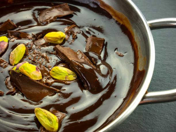 chocolate negro derretido con pistachos. salsa con mousse de cacao. chocolate líquido. cocinar dulces en casa. prepara un postre. crema caliente de cacao. vista superior de cerca. - chocolate pot de creme fotografías e imágenes de stock