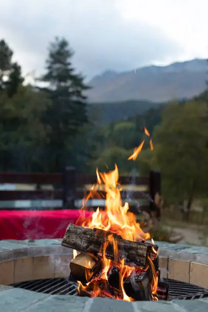 Photo of burning bonfire in a fire pit in the evening light and mountain views