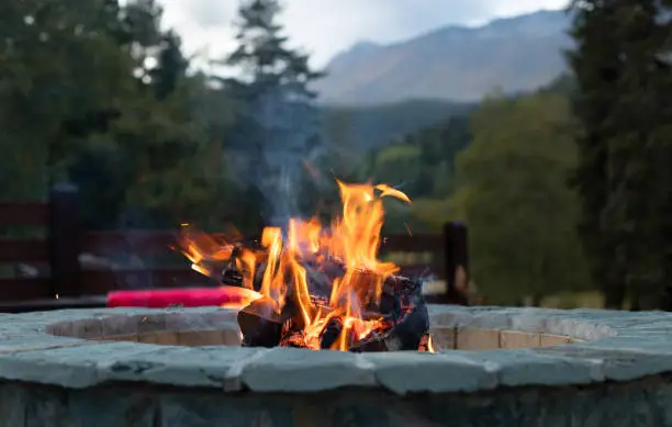Photo of close-up fire flame in a fire pit and mountains in the background