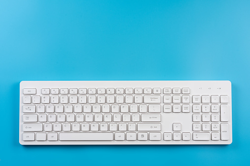 Top view of white english keyboard isolated on light blue or cyan background color
