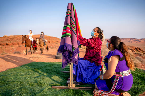 navajo großmutter lehrt ihre enkelin, wie man eine traditionelle decke auf einem webstuhl draußen in der wüste im northern arizona monument valley tribal park in dusk webt - navajo national monument stock-fotos und bilder