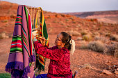 Elderly Navajo Woman Weaving a Traditional Blanket or Rug on an Authentic Native American Loom in the Desert at Dusk near the Monument Valley Tribal Park in Northern Arizona