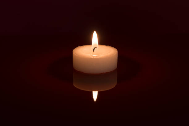 одноместный белый горящий чайный свет с его отражением на черном фоне - tea light candle white single object стоковые фото и изображения