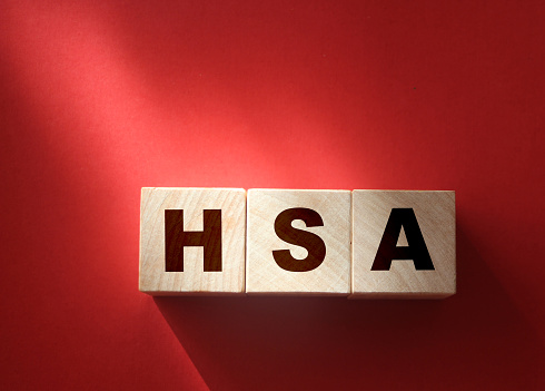 HSA abbreviation is written on wooden cubes on red backgrond. Concept. Health Savings Account.