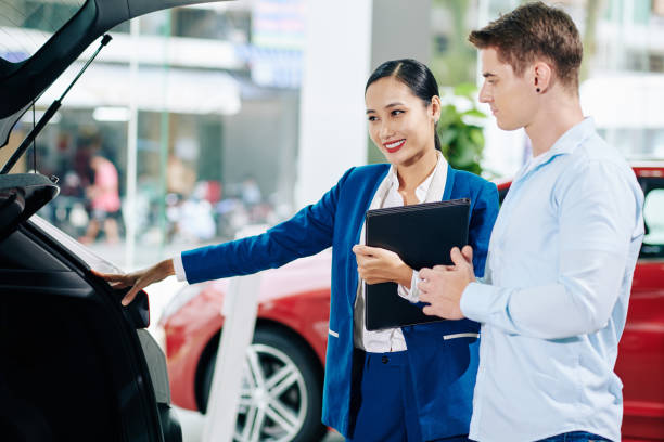 istock Dealership manager opening car trunk 1278439516