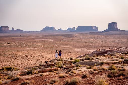 Dos adolescentes navajo niñas nativas americanas mirando sobre el vasto desierto en el norte de Arizona Monument Valley Tribal Park Navajo Reserva photo