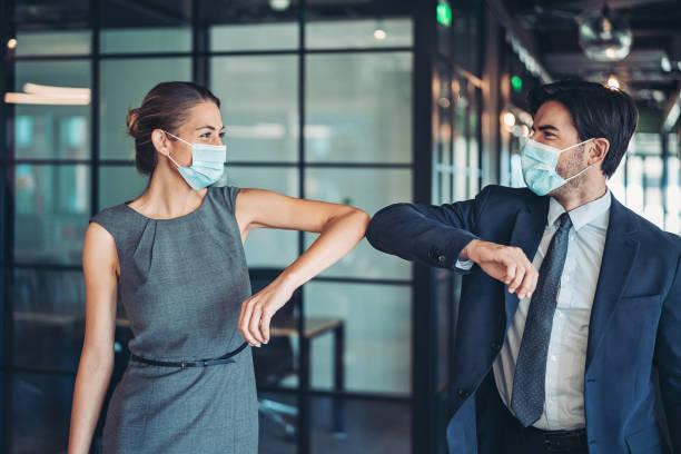 Couple of business persons greeting with an elbow bump Couple of business persons touching elbows in the office elbow photos stock pictures, royalty-free photos & images