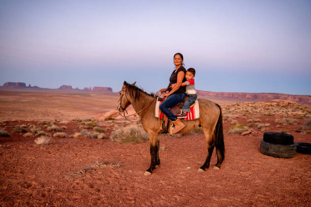 navajo madre e young four year old son in posa a cavallo davanti al buttes nel monument valley tribal park nel nord dell'arizona al tramonto - cherokee foto e immagini stock