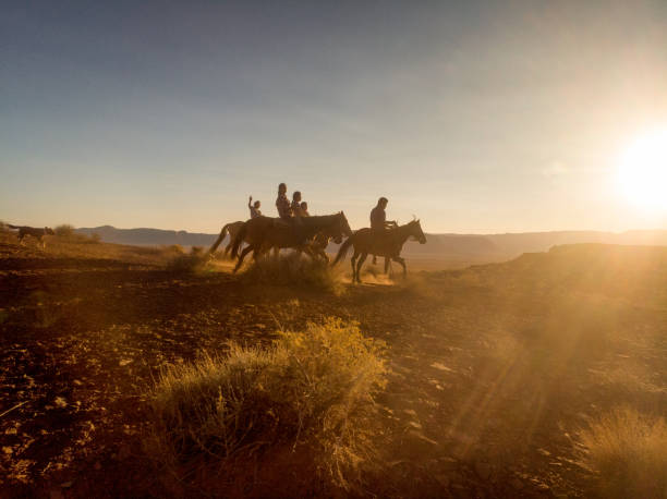 grupo de jóvenes hermanos navajos cabalgando sus caballos desnudos a través del vasto desierto en el norte de arizona cerca del parque tribal monument valley en la reserva india navajo al atardecer - navajo national monument fotografías e imágenes de stock