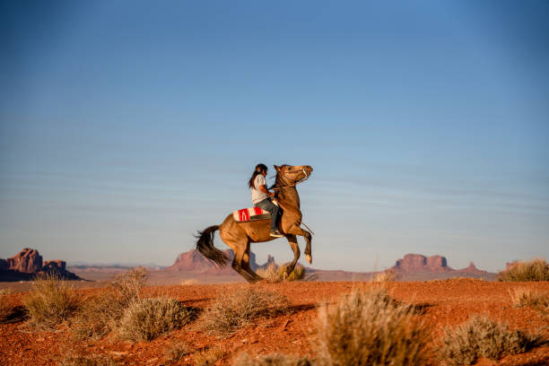 junge navajo teenage boy fachmännisch reiten sein pferd machen es buck in der wüste in der northern arizona navajo reservation in monument valley tribal park - navajo national monument stock-fotos und bilder