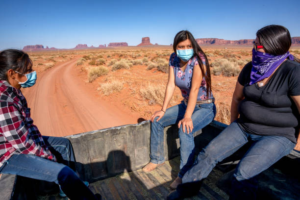 tres jóvenes teenage navajo sisters cabalgando en la cama de una camioneta usando máscaras covid-19 para aplanar la curva y detener la propagación del virus corona - navajo national monument fotografías e imágenes de stock