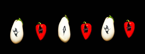 istock White eggplant and red bell pepper with paper figures for Halloween on black background. Holidays in the Time of COVID. 1278443131