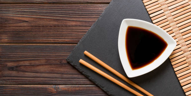 istock Chopsticks and soy sauce on black stone plate, wooden background with copy space 1278444549