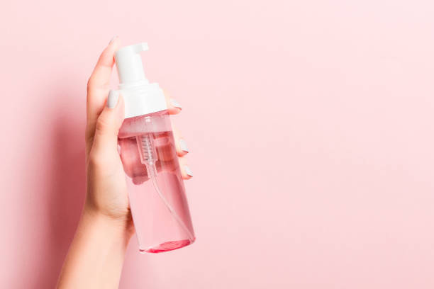istock Woman's hand is holding a cosmetics spray at pink background with copy space for your design 1278444561