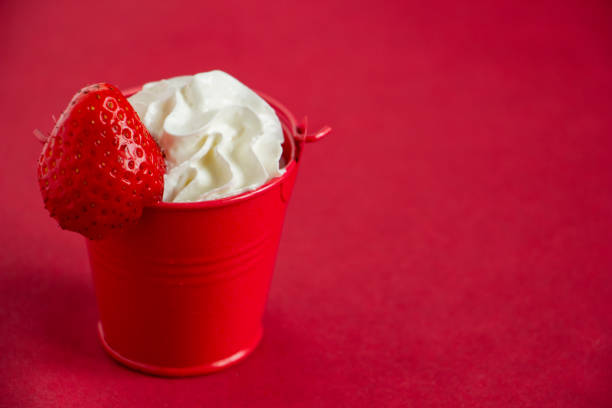 appetizing dessert in a red bucket on a red background, unusual table setting, whipped cream with strawberries unusual dessert serving - whipped cream in a bucket, delicious strawberries. juicy, bright, appetizing and stylish. High quality photo unusual basket stock pictures, royalty-free photos & images