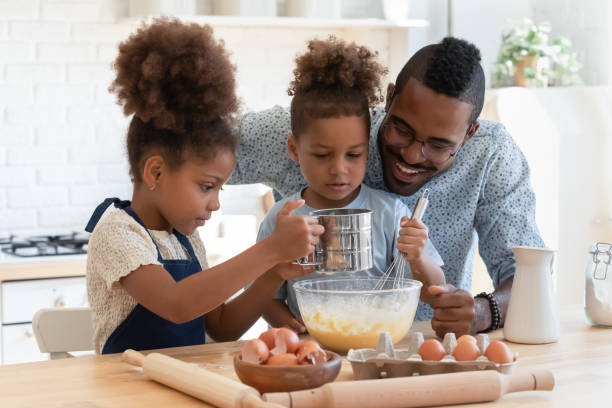 istock Happy african american man preparing dough with kids. 1278444946