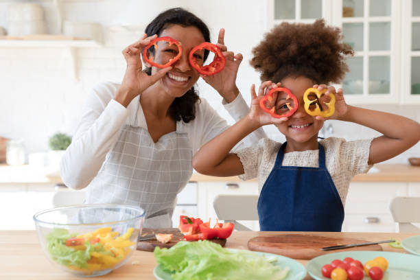 felice famiglia afroamericana che si diverte in cucina. - mother enjoyment built structure human head foto e immagini stock