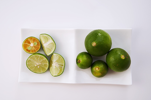 Close-up photo of slices green lime in a red plate, usually served with other dishes like traditional Javanese chicken soup or Soto. This lime also used as herbal medicine and contains vitamin C.