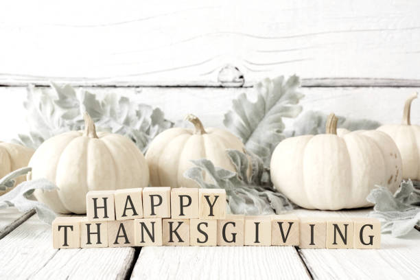 salutation heureuse de thanksgiving contre le bois blanc avec des citrouilles blanches et des feuilles d’automne - color image thanksgiving photography harvest festival photos et images de collection