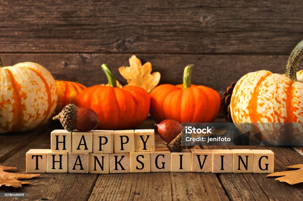 Happy Thanksgiving greeting against rustic wood with pumpkins and autumn leaves Happy Thanksgiving greeting on wooden blocks against a rustic wood background with pumpkins and autumn leaves Thanksgiving - Holiday Stock Photo