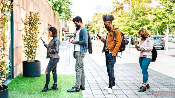 giovani in fila che praticano il distanziamento sociale al negozio della città - nuovo concetto di stile di vita normale con persone che indossano la maschera facciale in coda urbana - filtro retroilluminazione luminoso - persone in fila foto e immagini stock