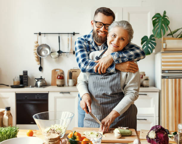 自宅で健康的な夕食を準備大人の息子と幸せな主婦 - grandmother senior adult family domestic kitchen ストックフォトと画像