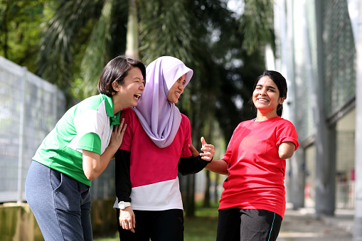 A multi-ethnicity friends - Muslim, Chinese and Indian (amputated left limb) ladies enjoying chatting and laugh to their heart's content.