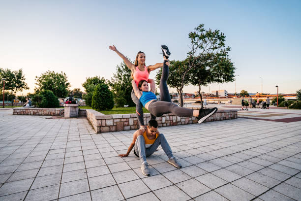 A smiling, young woman jumps with arms outstretched arms in the city.