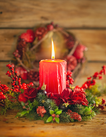 Burning Christmas red candle and  festive Christmas arrangement on a wooden table. Christmas advent