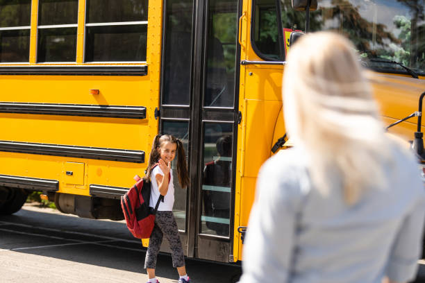 kinder schüler laufen in die hände der mutter, um sie zu umarmen, nachdem sie wieder in der nähe des schulbusses - front view bus photography day stock-fotos und bilder