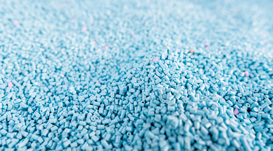 Close up large pile of blue plastic granules in temporary storage of production line at recycle factory, masterbatch dye polymer plastics resin pellet background,  injection molding process lab