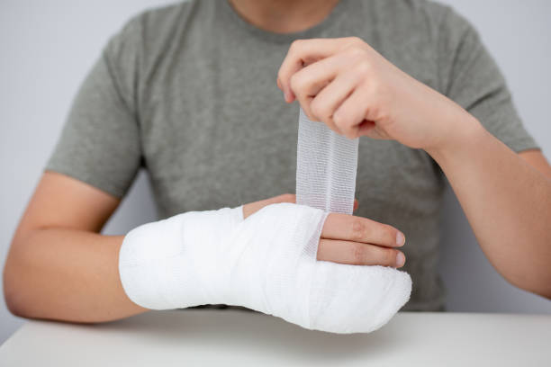 concept de premiers soins - homme bandant sa main - physical injury bandage wound cast photos et images de collection