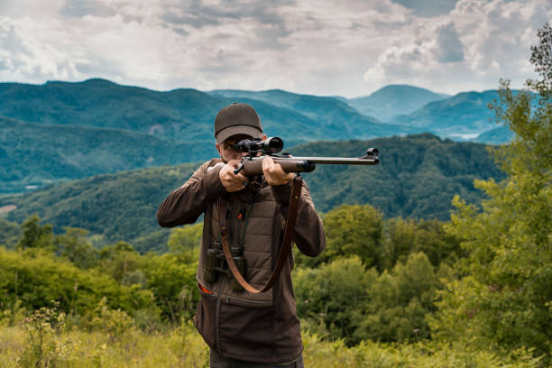 cacciatore che punta a un colpo con un fucile di precisione in alto nella regione montuosa - rifle hunting gun aiming foto e immagini stock