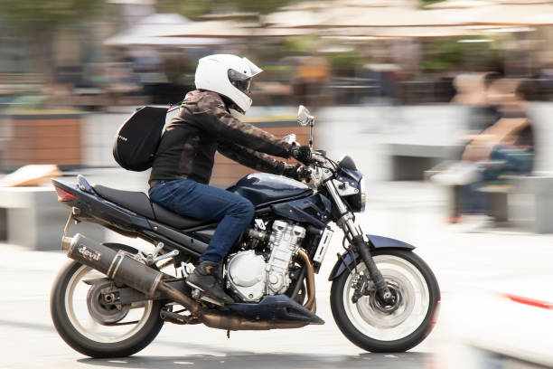 man riding a fast motorbike on the street by city square, panning shot - motorcycle biker riding motorcycle racing imagens e fotografias de stock