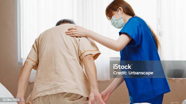 Female Asian Nurse Support Senior Male Patient Stand Up And Walk From Bed In Hospital Nursing Home Medical Service Physiotherapy Hospitality Or Recovery Treatment Concept Stock Photo - Download Image Now