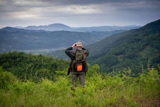 Hunter using binoculars too look for wildlife in the distance stock photo