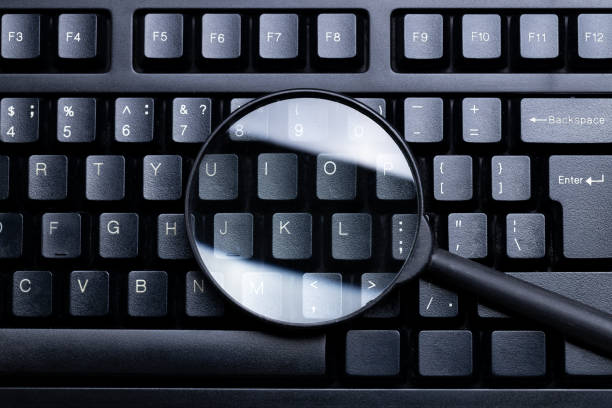 istock network search conceptual. discover online resources. magnifying glass on a black pc keyboard. above view. minimal 1278472548