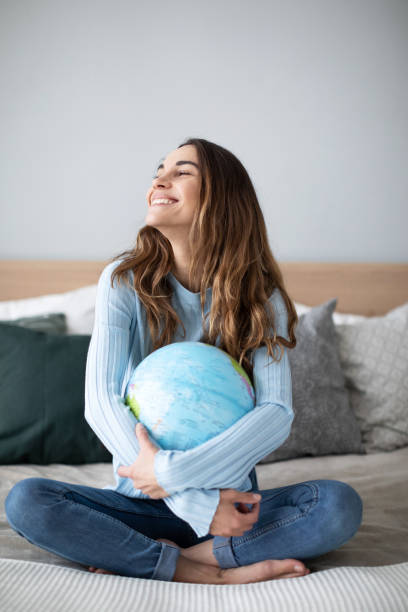 istock Woman is planning a trip, hugging globe sitting on the couch. 1278473640
