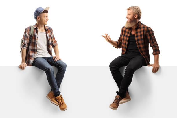 istock Bearded guy sitting on a white panel and talking to a young male student 1278473726
