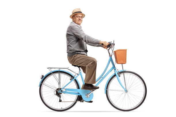 Happy active senior man riding bicycle in the park. Smiling senior man having fun riding vintage bike outdoors on sunny day.