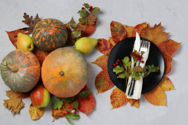 istock Table setting on Thanksgiving Day decorated pumpkin, viburnum, pears and colorful leaves on grey. Top view 1278475246
