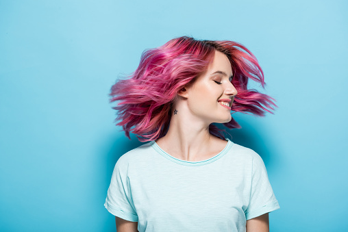 joven agitando el pelo rosa sobre el fondo azul photo