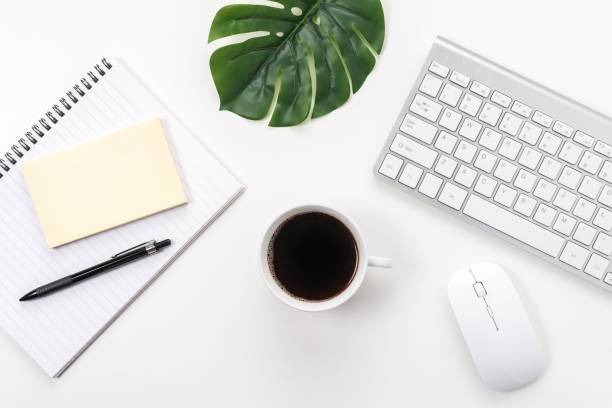 istock Workspace with computer keyboard, office supplies, green leaf, and coffee cup on white background. 1278484988