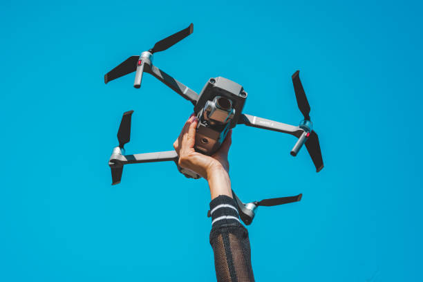 woman hand holding dji mavic 2 pro drone or quadcopter isolated on the blue sky background. 29.09.2020, netherlands, amsterdam - aero imagens e fotografias de stock